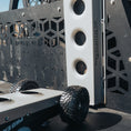 Load image into Gallery viewer, Black heavy-duty jack with textured grip and thick off-road tire against patterned metal backdrop.