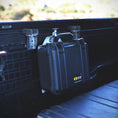 Load image into Gallery viewer, Black hard-shell Pelican Protector 1400 case mounted inside vehicle cargo area with secure black mounting brackets.
