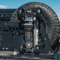 Load image into Gallery viewer, Black and silver Pro Eagle 2 Ton jack mounted on truck bed with large off-road tire in background.
