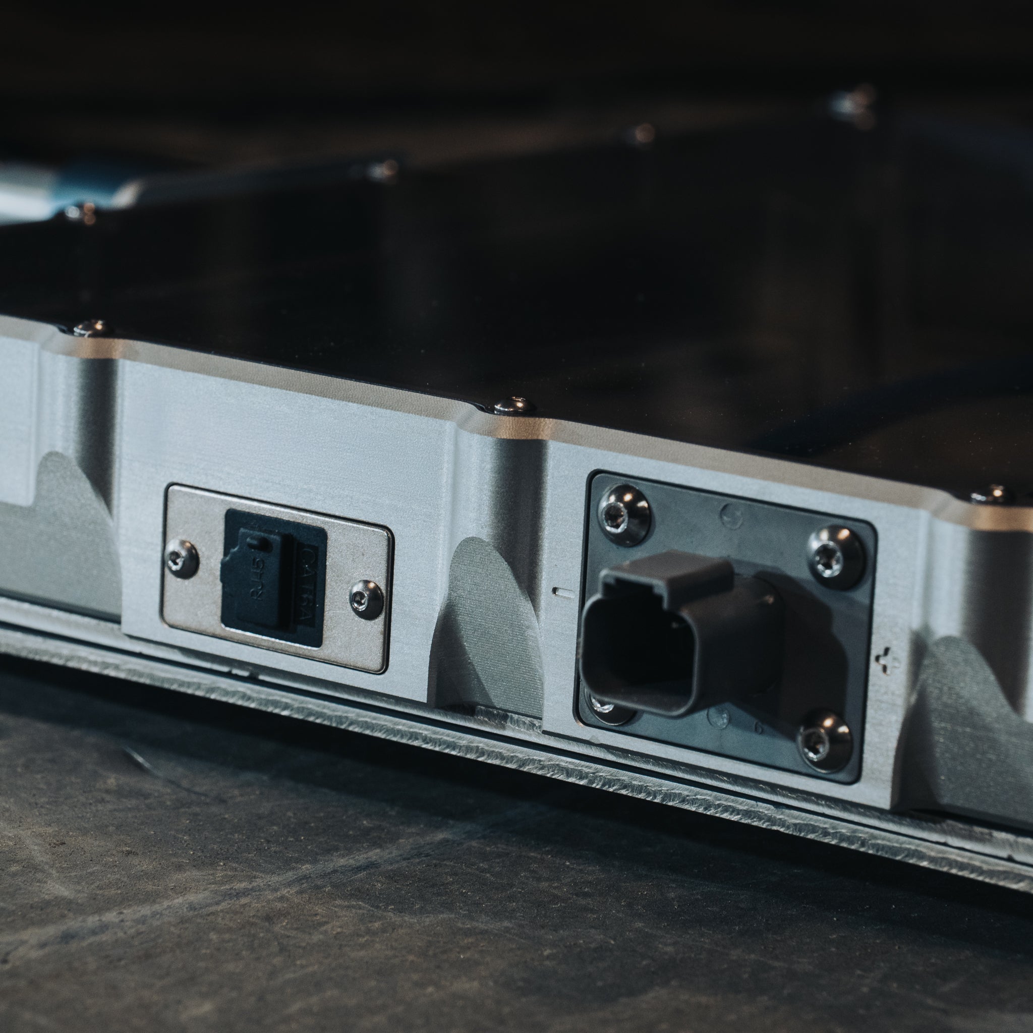 Metal Starlink Mini mount with power and data ports on a dark surface.