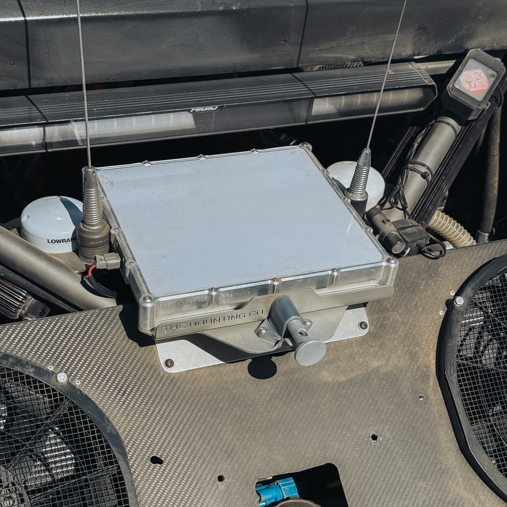 Compact metal Starlink Mini Mount secured on textured black surface with antenna connections and cooling fans nearby.