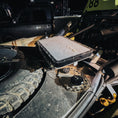 Load image into Gallery viewer, Black aluminum quick-release Starlink mount attached to off-road vehicle with rugged tire nearby and surrounding gear.
