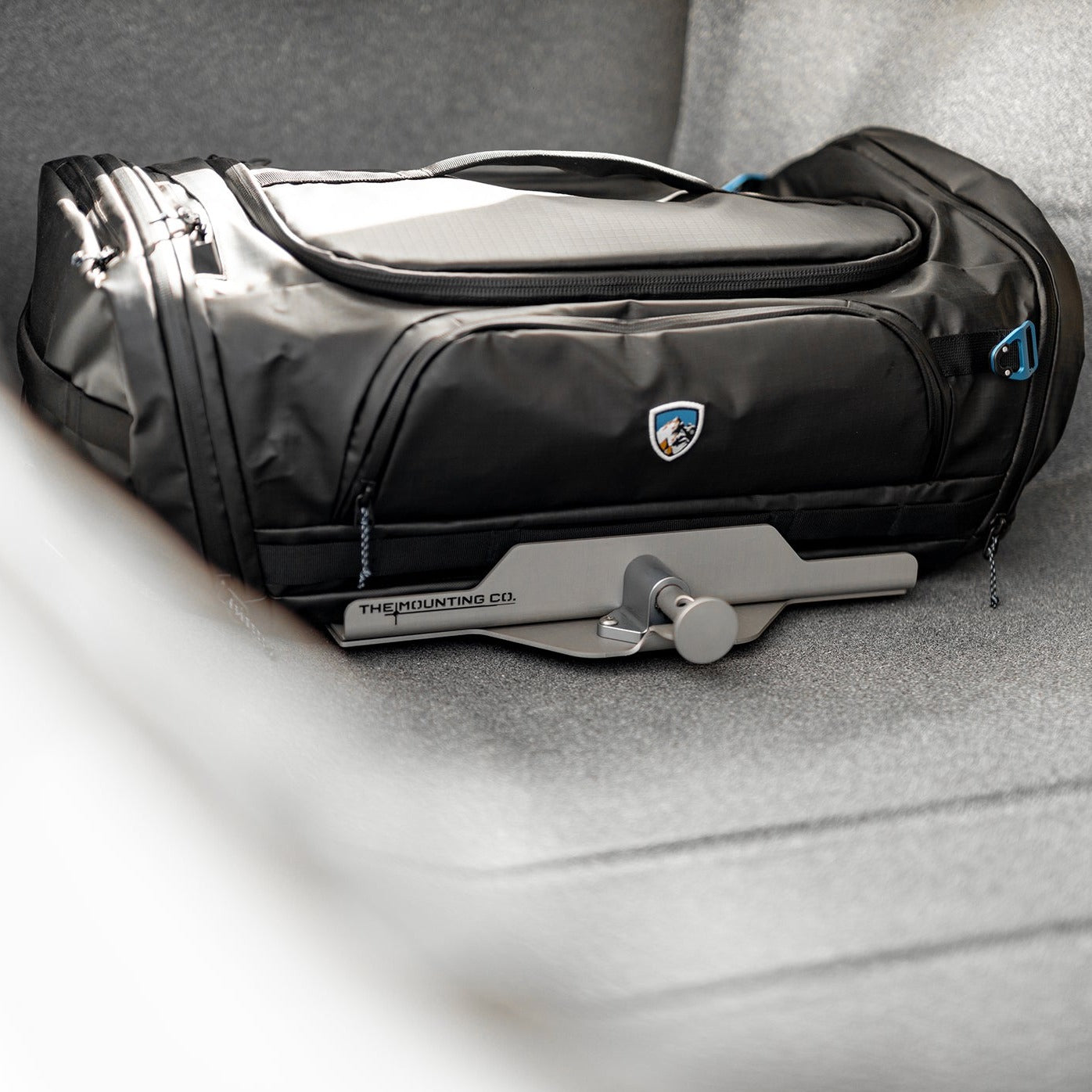 Black rugged XL Mount bag with secure gray quick-release mounting bracket on gray fabric surface.