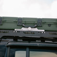 Load image into Gallery viewer, Black aluminum roof rack mount securely holding a large green military-style storage case with latches.
